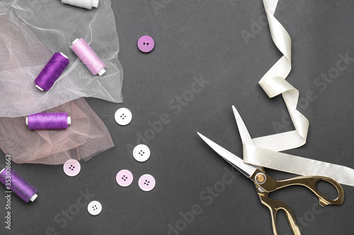 Scissors with sewing items on dark background