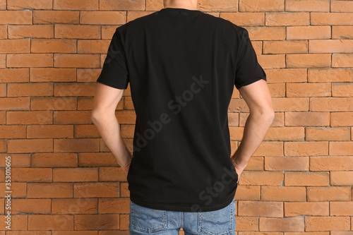 Man in stylish t-shirt near brick wall
