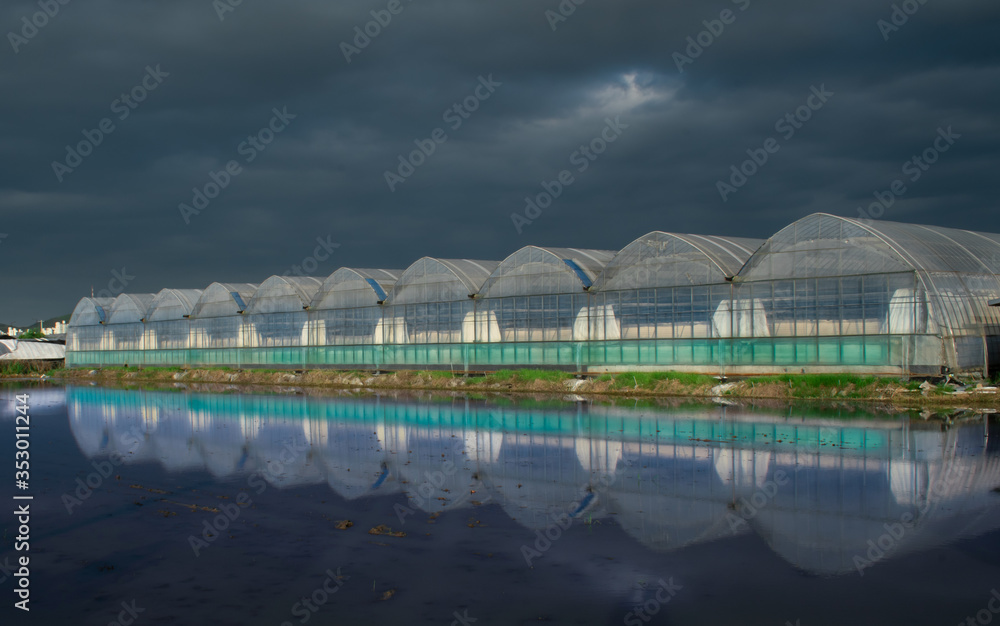 Dark, storm clouds loom over a row of greenhouses on the rural farmland of Goyang, South Korea. 