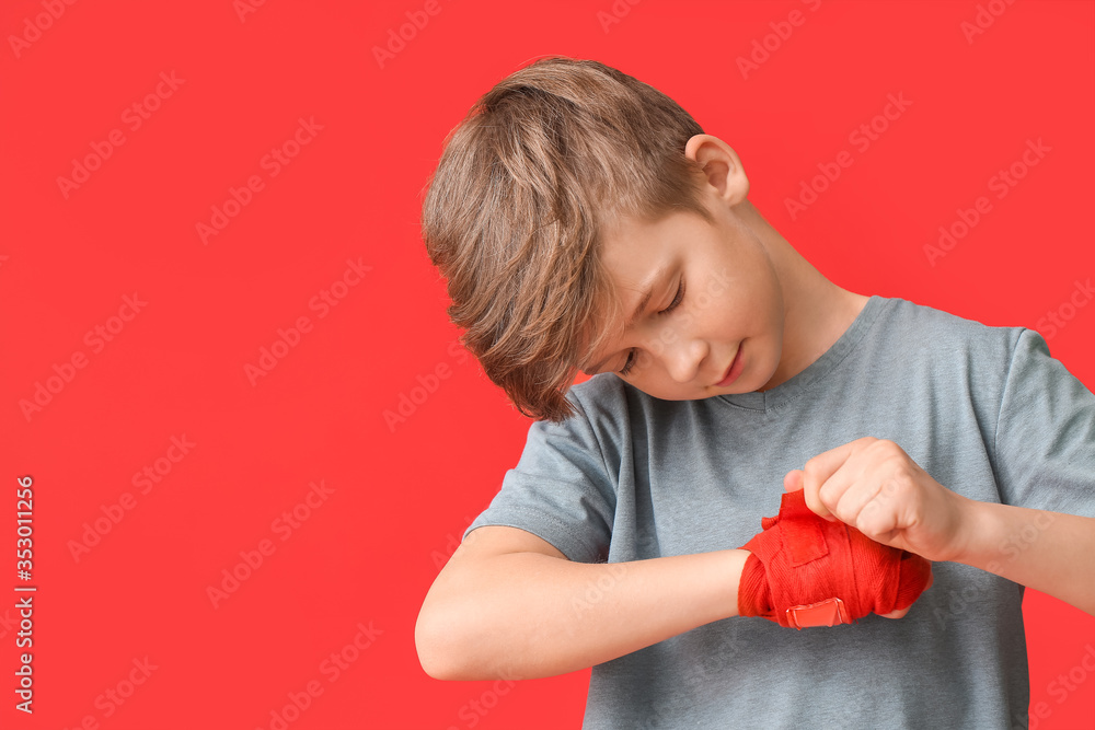 Cute little boy applying wrist bands against color background Cute little boy applying wrist bands against color background