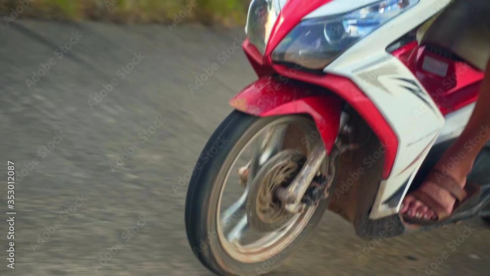 Closeup a young person's foot, scooter, wheel and fender on uneven pavement, Bokor National Park, slow motion Closeup a young person's foot, scooter, wheel and fender on uneven pavement, Bokor National Park, slow motion