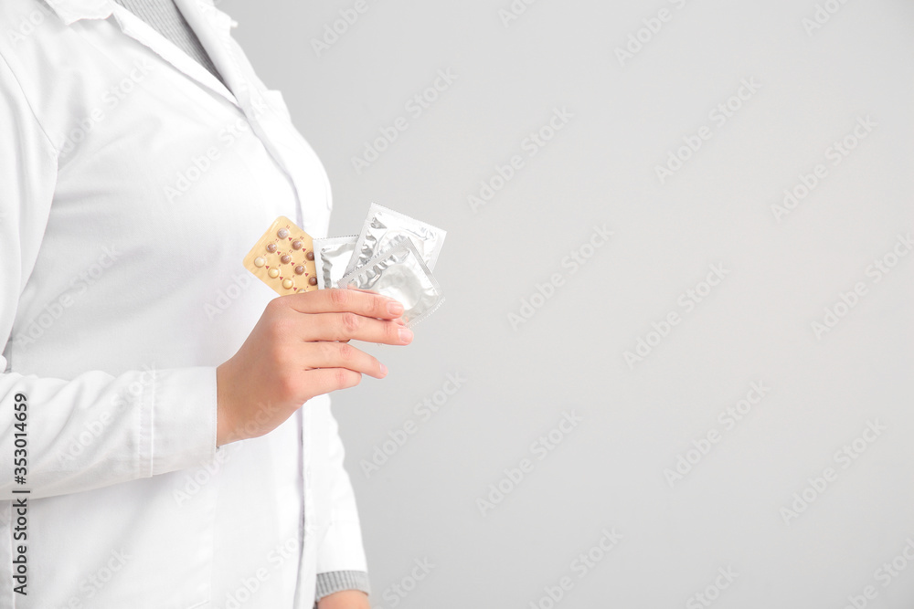 Female gynecologist with different contraceptives on grey background, closeup Female gynecologist with different contraceptives on grey background, closeup