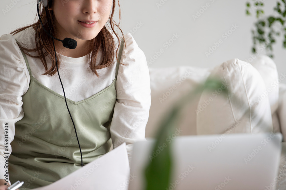ヘッドセットマイクをつけてテレビ電話する女性 ヘッドセットマイクをつけてテレビ電話する女性