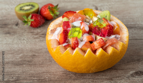 fruit salad in a pot made from grapefruit. fruit food on a wooden background.
