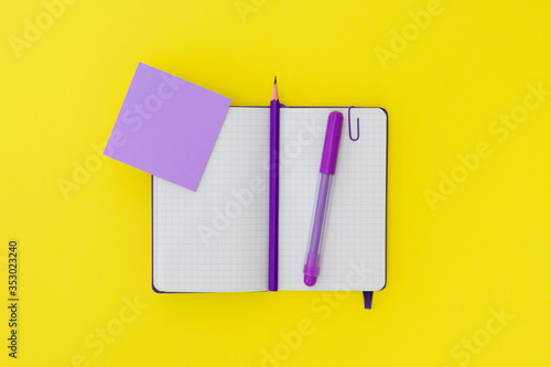 Purple notepad, pencil and marker on a yellow background. Copy space, flat lay. Concept office and back to school.