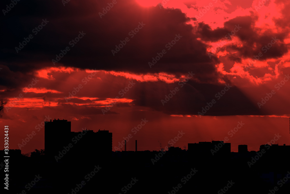 dark buildings in the rays of the setting sun in red tinted. dark buildings in the rays of the setting sun in red tinted.