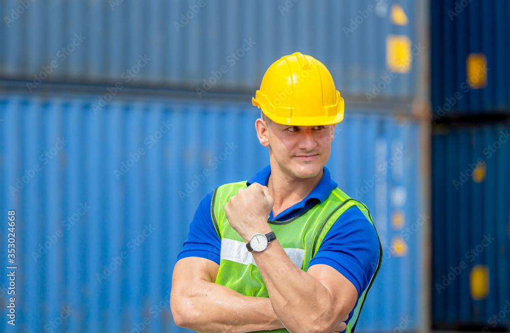 Happiness foreman worker in hardhat show strong arm muscles at containers cargo on a hot day Happiness foreman worker in hardhat show strong arm muscles at containers cargo on a hot day