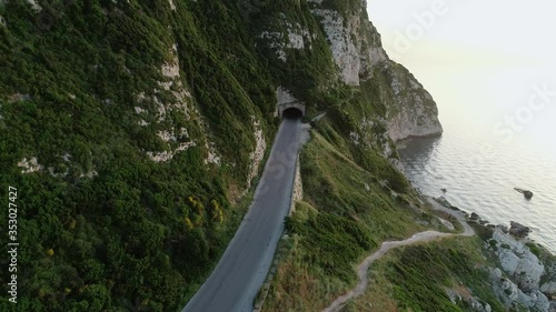 Empty seaside rocky coastline road by sea into narrow tunnel, approaching aerial, Chekka, Lebanon photo