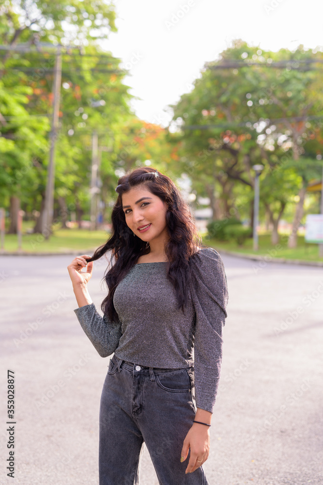 Happy young beautiful Indian woman smiling in the streets at the park Happy young beautiful Indian woman smiling in the streets at the park