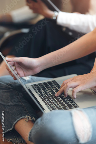 Cropped shot of young female university student using laptop computer while sitting on the floor in library.