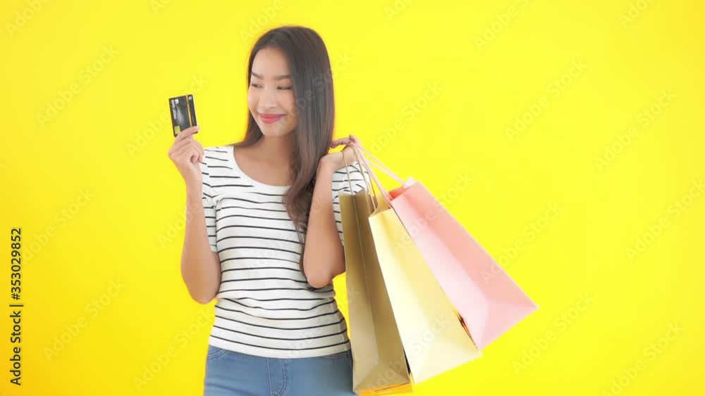 Portrait of Happy Asian Female With Shopping Bags and Credit Card, Isolated on Yellow Chromakey Background Portrait of Happy Asian Female With Shopping Bags and Credit Card, Isolated on Yellow Chromakey Background