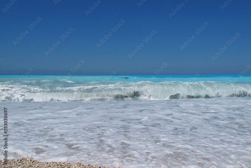 Romantic view of the sea waves, with blue beautifull water, white foam and yellow sand. Beautiful texture shot for background from Kefalonia island, Greece. Romantic view of the sea waves, with blue beautifull water, white foam and yellow sand. Beautiful texture shot for background from Kefalonia island, Greece.