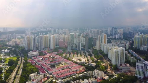 Smooth, steady, aerial drone directional forward flight over green trees, futuristic Singapore city skyline apartment skyscrapers and high rise buildings, street construction developments. Moody light photo