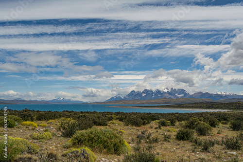 llanura con vista a lago colorido con fondo a monta  as y grandes nubes. Parque Torres del Paine  Chile 