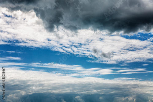A black cloud hanging over a bright blue cloudy sky on a sunny day. Background. Space for text.