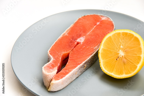 Close up fresh raw salmon steak with lemon slice isolated on white background