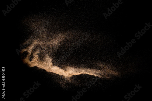 Golden sand explosion isolated on black background. Abstract sand cloud. Golden colored sand splash against dark background. Yellow sand fly wave in the air.