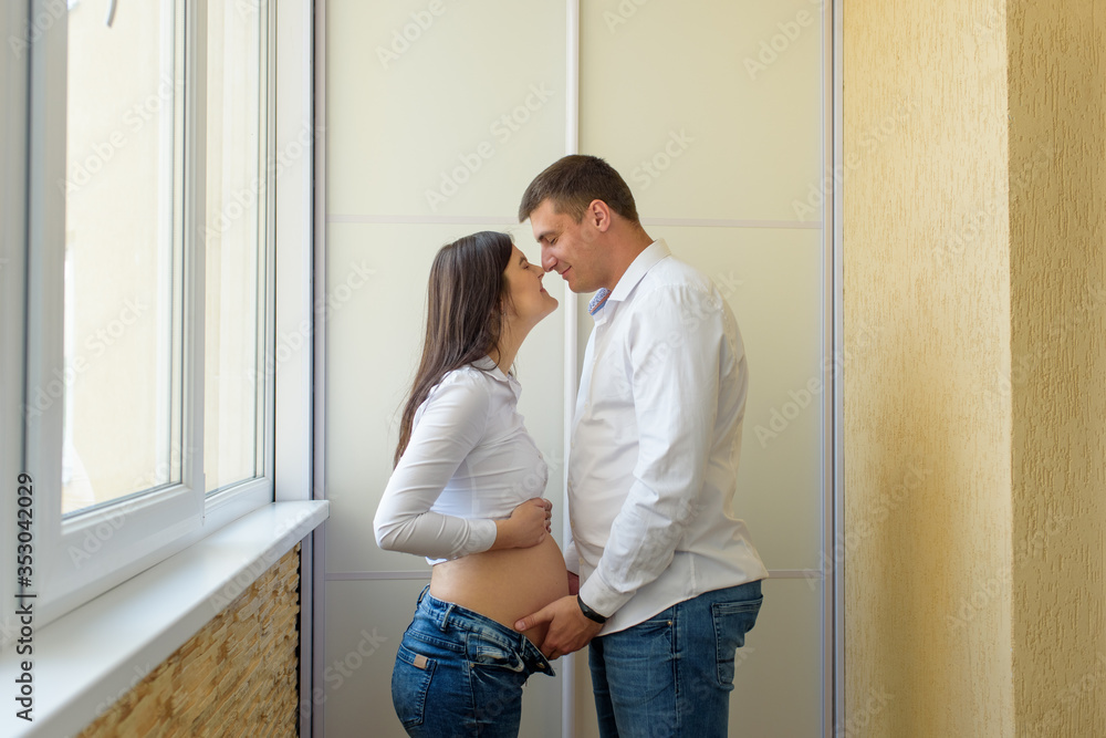 Husband and his pregnant wife. The couple is facing each other. A man holds his hands on a pregnant belly. Husband and his pregnant wife. The couple is facing each other. A man holds his hands on a pregnant belly.