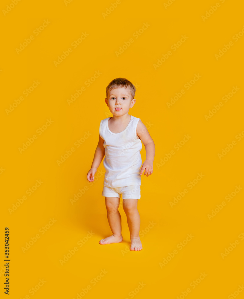 Little boy stands in a white T-shirt and underpants on an orange-yellow background Little boy stands in a white T-shirt and underpants on an orange-yellow background
