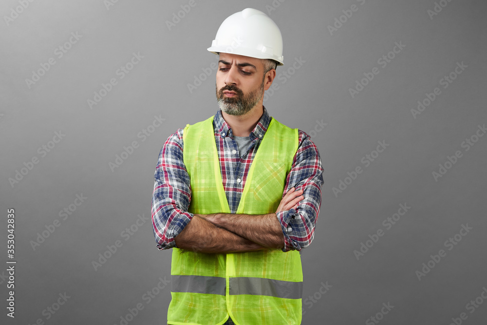 Bearded repair man standing with hands crossed on grey background
