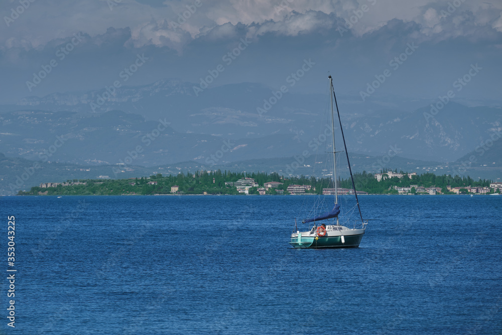Boat sailboat on the background of mountains. Lake Garda, Italy