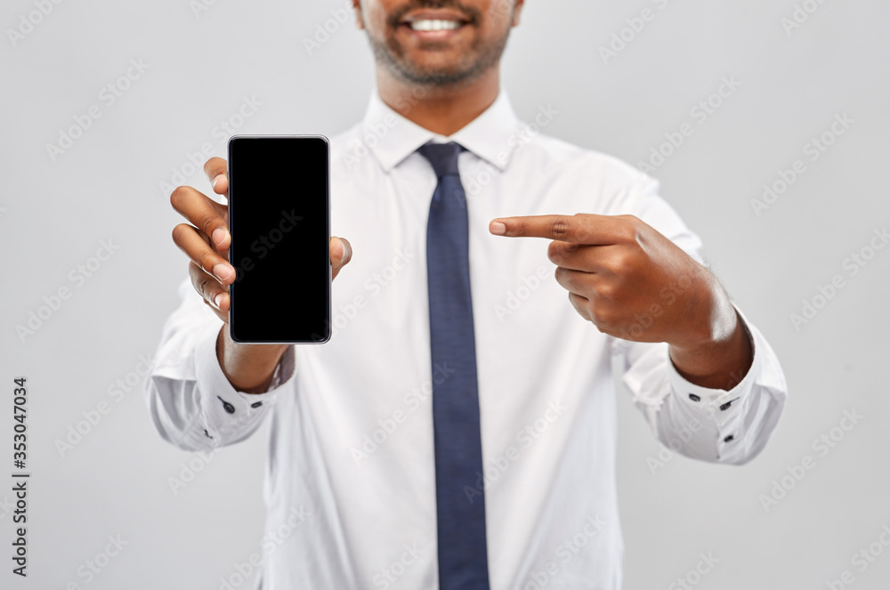 business, technology and people concept - close up of smiling indian businessman showing black smartphone screen over grey background business, technology and people concept - close up of smiling indian businessman showing black smartphone screen over grey background