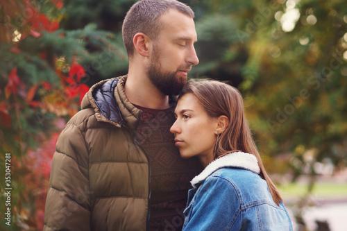 Young couple in love on romantic date in autumn park. Against backdrop of colorful autumn foliage. Lovers fall background. Leisure together. Young people.