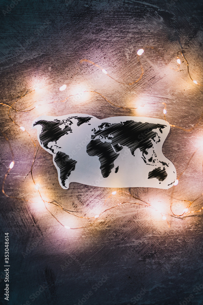 Fototapeta premium world map surrounded by fairy lights on concrete desk