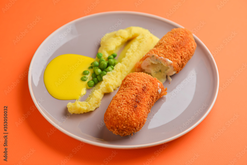 Cordon bleu cutlet, deep fried meat served with mashed potatoes and green peas on gray plate over orange background. Cordon bleu cutlet, deep fried meat served with mashed potatoes and green peas on gray plate over orange background.