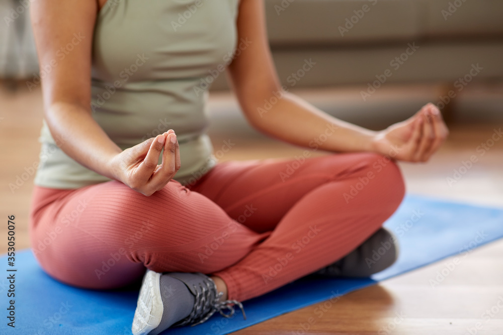 yoga, mindfulness and healthy lifestyle concept - close up of young african american woman meditating in lotus pose at home yoga, mindfulness and healthy lifestyle concept - close up of young african american woman meditating in lotus pose at home