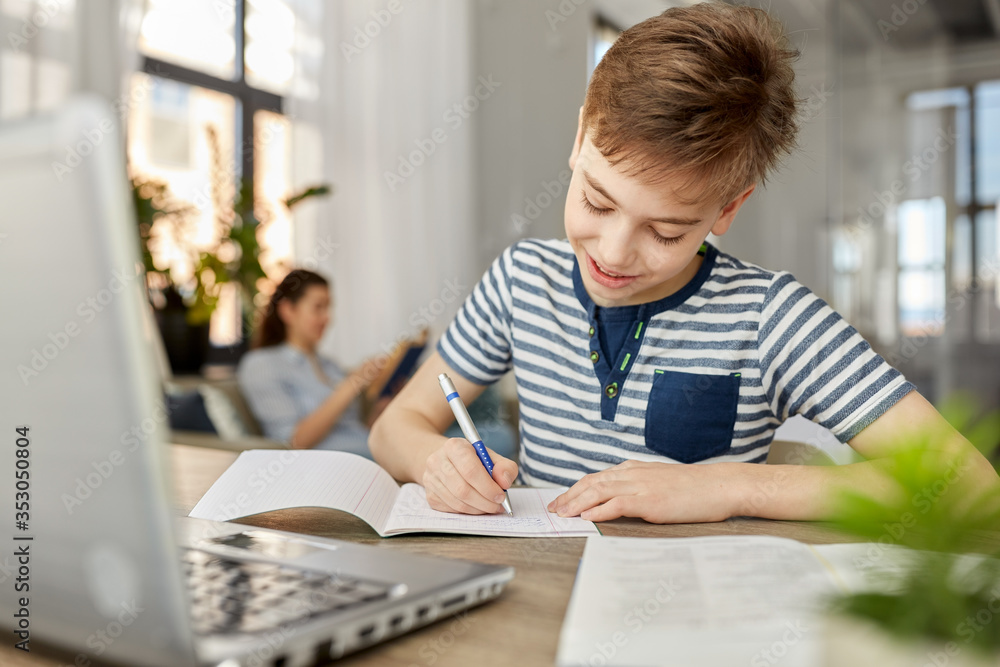 children, education and learning concept - happy smiling student boy with book writing to notebook at home children, education and learning concept - happy smiling student boy with book writing to notebook at home
