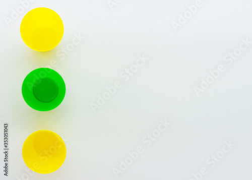 Colorful plastic cups, the view from the top. Yellow and green glass. Composition of plastic dishes. Minimalistic design with space for text. Isolated on a white background.