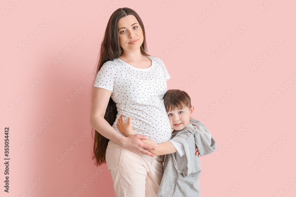 Beautiful pregnant woman with her little son on color background Beautiful pregnant woman with her little son on color background