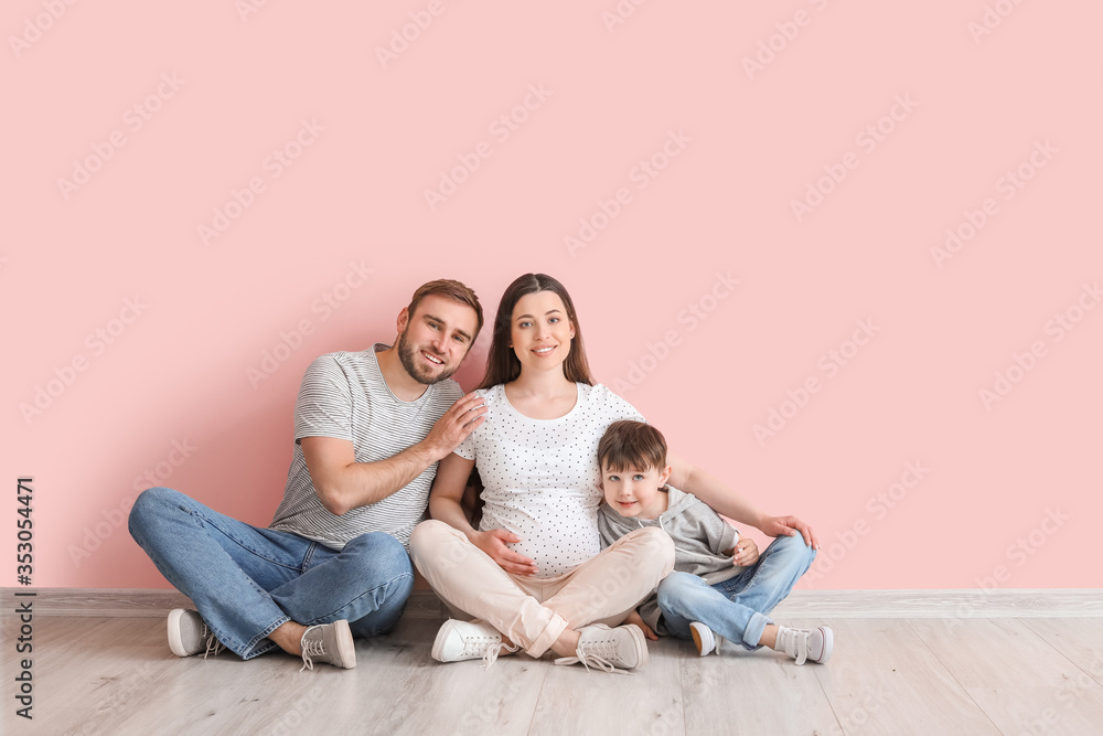 Beautiful pregnant woman with her family sitting near color wall Beautiful pregnant woman with her family sitting near color wall