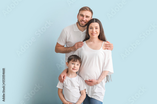 Beautiful pregnant woman and her family on color background © Pixel-Shot