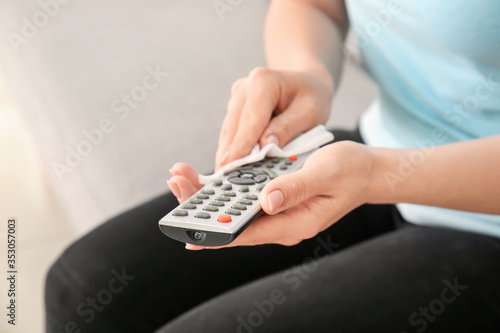 Woman disinfecting remote control at home