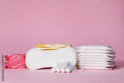 stack of menstrual sanitary cotton pads and tampon on pink background. Feminine hygiene products. copy space.