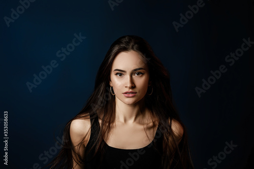 portrait of beautiful young woman with long flying hair on dark blue background