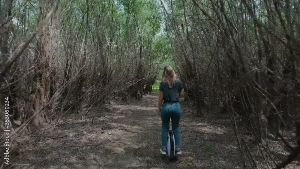 Girl riding an electric unicycle through a creepy forest Girl riding an electric unicycle through a creepy forest