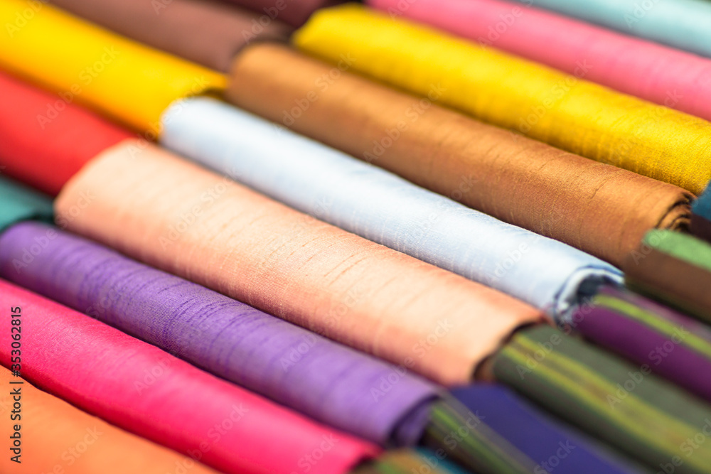 Closeup of a variety of colored fabrics folded and displayed in a shop. Closeup of a variety of colored fabrics folded and displayed in a shop.