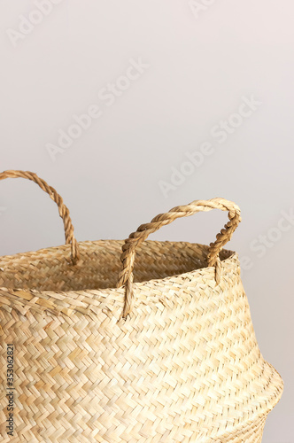 Empty straw wicker basket on a gray background. Fashionable bamboo basket, stylish interior item, eco design, handmade. Natural decor of the interior, home. Natural eco materials, storage basket