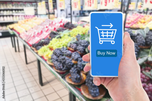 In the supermarket, close-up of a man's hand holding a mobile phone to shop online.