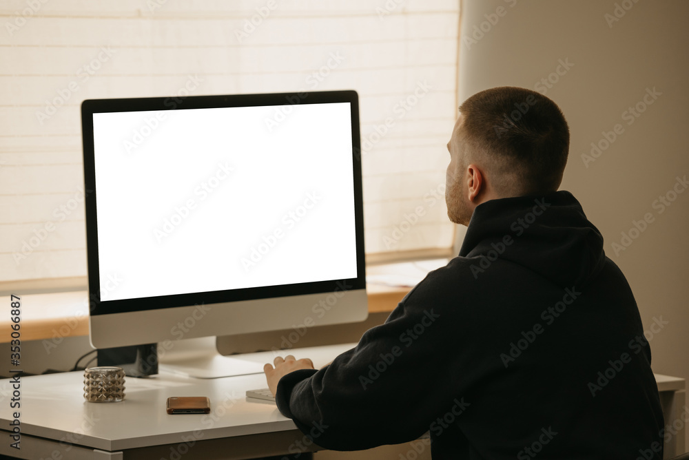 Remote work. A back view of a businessman works remotely using an all-in-one computer. A fellow working from home.