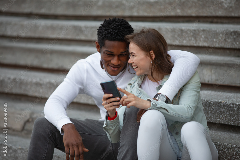 Two multiracial friends looks photos in smartphone Two multiracial friends looks photos in smartphone