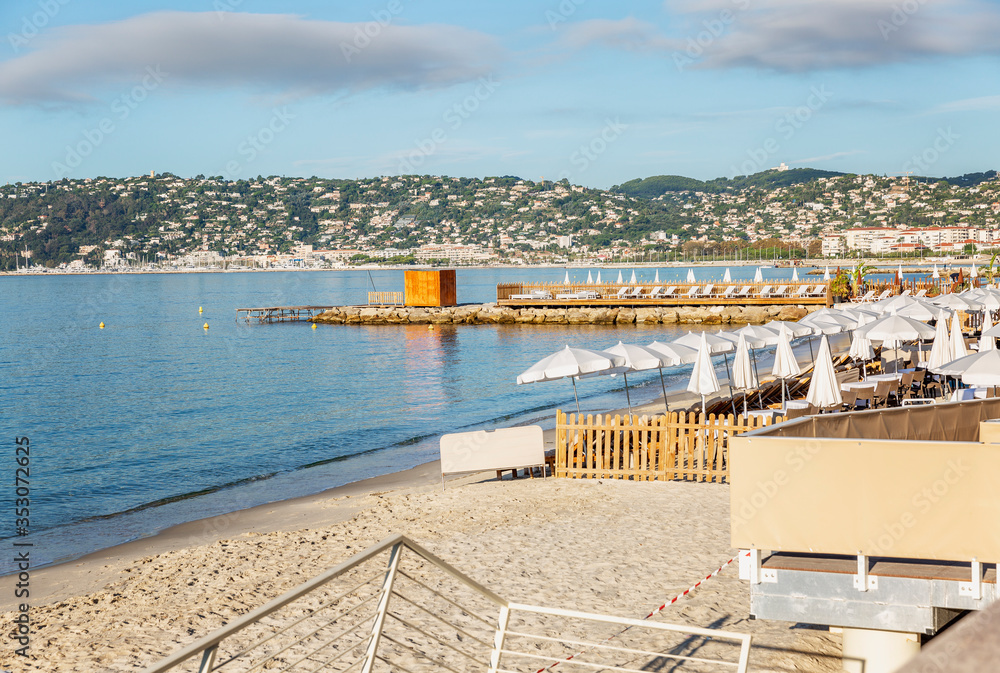 Sandy beach with sun loungers on the azure shore of the Mediterranean Sea. Preparation for the tourist season on a sunny day. Sandy beach with sun loungers on the azure shore of the Mediterranean Sea. Preparation for the tourist season on a sunny day.