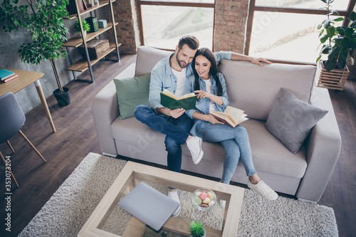 Top above high angle view full length photo of positive woman man sit couch read book girl point finger paperbook enjoy free time in house indoors photo