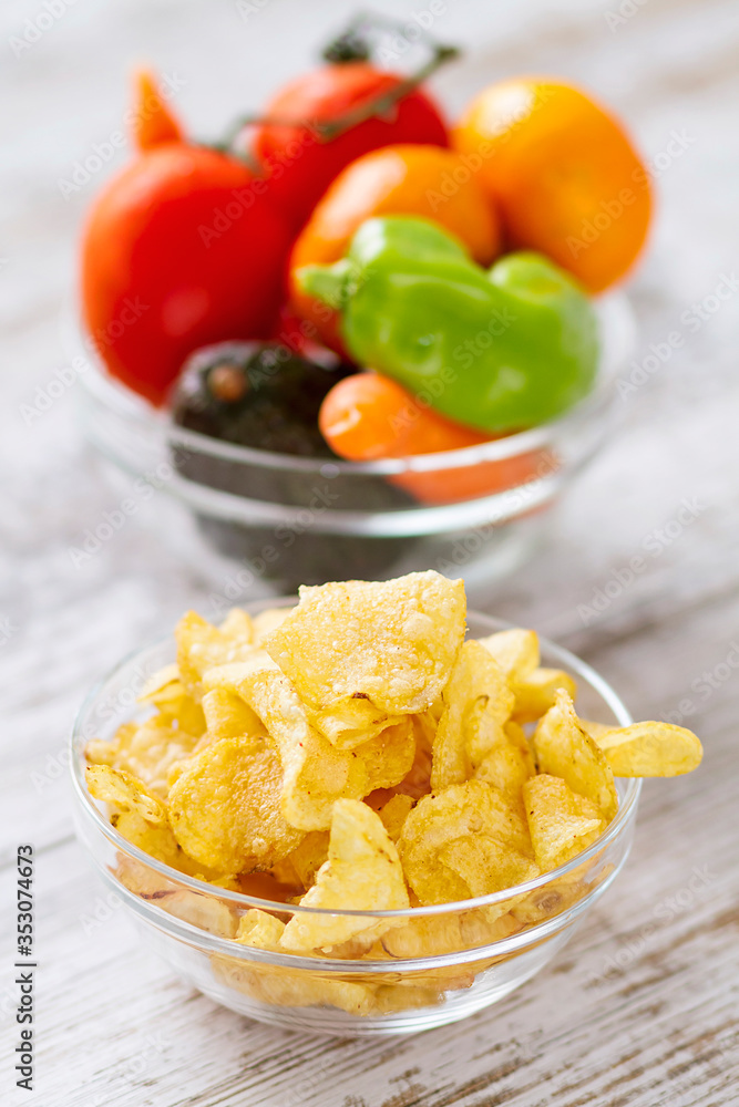 Fresh veteables in a bowl against potatoe chips Fresh veteables in a bowl against potatoe chips