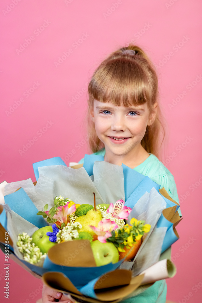 A little blonde girl of European appearance is holding a fruit bouquet in her hands. Fruit composition, fruit on skewers. A little blonde girl of European appearance is holding a fruit bouquet in her hands. Fruit composition, fruit on skewers.