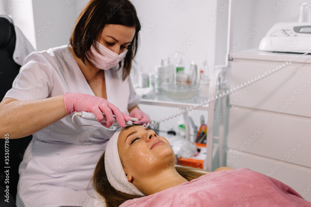 Ultrasonic scraber. Procedure of ultrasonic cleaning of face. Model, profile. Cosmetological clinic. Healthcare, clinic, cosmetology Ultrasonic scraber. Procedure of ultrasonic cleaning of face. Model, profile. Cosmetological clinic. Healthcare, clinic, cosmetology