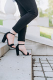 the girl goes down the steps of the light stairs black sandals and black trousers